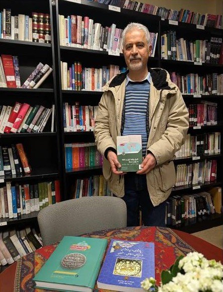 Dr. Javad Abbasi holding his book inside the library
